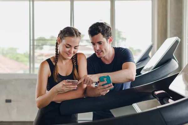 커플들은 체육관에서 운동을 근처에서 스마트폰을 가지고 즐겁게 부부들 — 스톡 사진