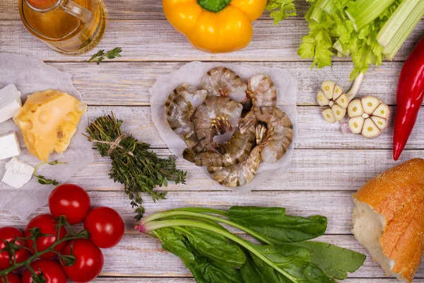 Overhead View of Shrimps, Spinach, Bell Pepper, Tomato Cherry, Bread, Garlic, Thyme, Olive Oil, Glass of White Wine, Celery and Feta Cheese on Rustic Wooden Background — Stockfoto