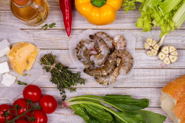 Overhead View of Shrimps, Spinach, Bell Pepper, Tomato Cherry, Bread, Garlic, Thyme, Olive Oil, Glass of White Wine, Celery and Feta Cheese on Rustic Wooden Background — Stock Fotó