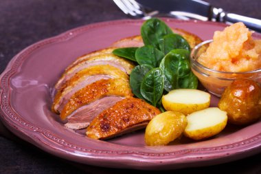 Ördek göğsü, elma sosu, ıspanak ve patates, pembe plaka üzerinde servis