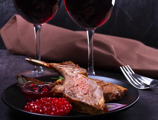 Grilled rack of lamb with pomegranate sauce in black plate — Stock Photo, Image