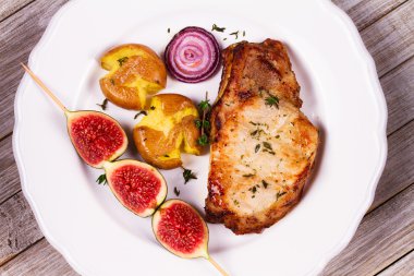 İncir ile kavrulmuş domuz pirzolası pişmiş patates, kırmızı soğan ve kekik