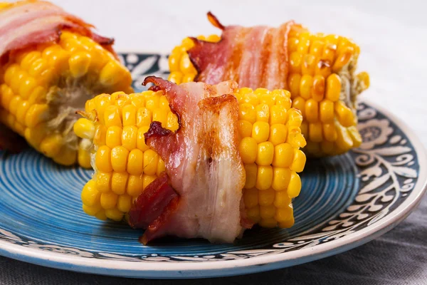Bacon-wrapped corn in blue plate — Stock Photo, Image