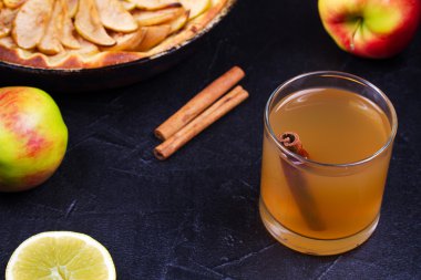 Elma, limon ve siyah arka plan üzerine tarçın elma suyu cam