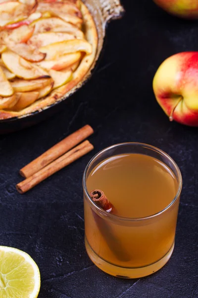 Cider glass with apples, lemon and cinnamon on black background — Stock Photo, Image