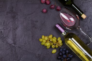 Kırmızı ve beyaz şarap kadehi ve şişe. Üzüm ve fındık siyah arka plan üzerine