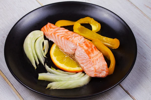 Gedämpfter Lachs mit Fenchel, Pfeffer und Orangen auf schwarzem Teller — Stockfoto