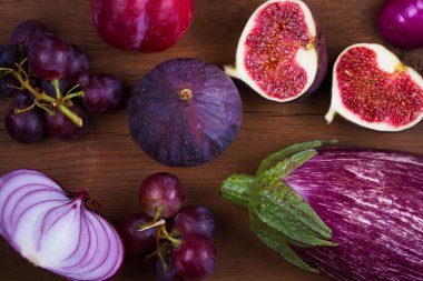 Olgun mor incir, Erik, üzüm, patlıcan ve soğan. Ahşap arka plan üzerinde meyve ve sebze natürmort