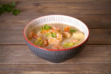 Tahta masadaki kasede yengeç etli karides çorbası. yatay resim