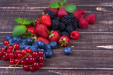 Çilek, yaban mersini, böğürtlen, ahududu, frenk üzümü ve nane ahşap arka plan üzerinde