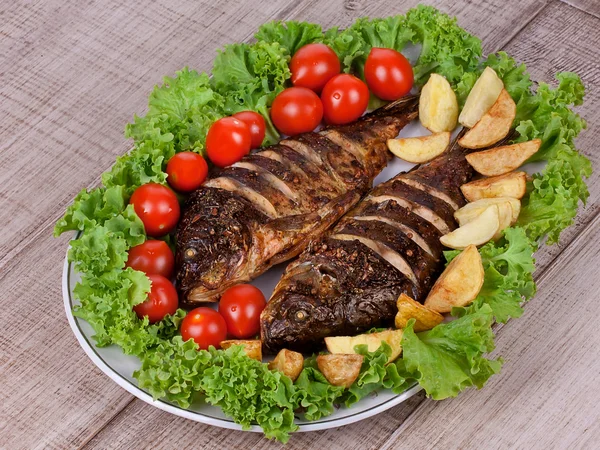 Whole grilled fish carp served with potatoes, tomatoes cherry and salad — Stock Photo, Image