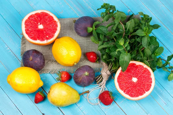 Grapefruit, körte, citrom, füge, eper, pomelo és a menta a fából készült háttér. Csendélet gyümölcsökkel — Stock Fotó