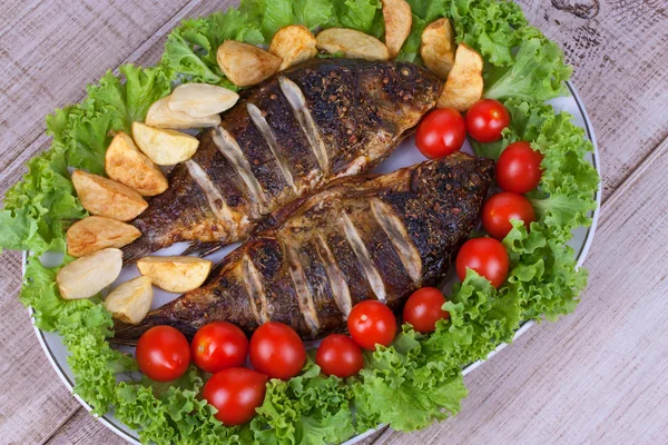 Whole grilled fish carp served with potatoes, tomatoes cherry and salad — Stock Photo, Image