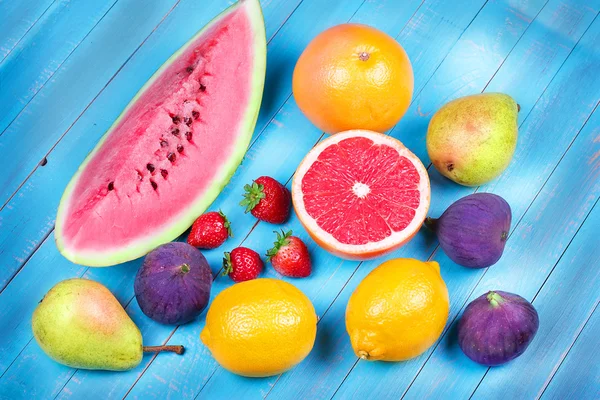 Toranjas, peras, limões, figos, morango, pomelo e hortelã sobre fundo de madeira — Fotografia de Stock