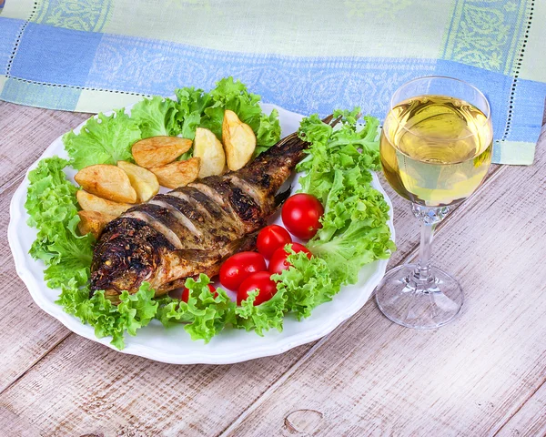 Whole grilled fish carp served with potatoes, tomatoes cherry, salad and lemon — Stock Photo, Image