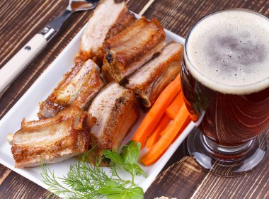 Izgara domuz pirzola ve bardak bira ahşap arka plan üzerinde