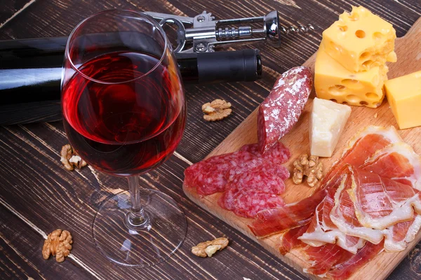 Verre et bouteille de vin, fromage et prosciutto sur fond bois. Nature morte — Photo