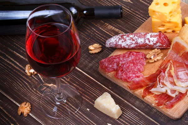 Γυαλί και μπουκάλι κρασί, τυρί και προσούτο σε ξύλινα φόντο. Νεκρή φύση — Φωτογραφία Αρχείου
