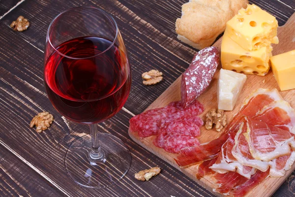 Verre et bouteille de vin, fromage et prosciutto sur fond bois. Nature morte — Photo