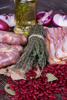 Barbunya, kekik, sosis ve ahşap zemin üzerine pastırma