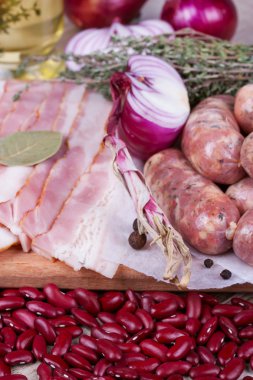 Barbunya, kekik, sosis ve ahşap zemin üzerine pastırma