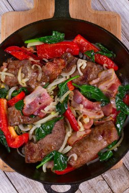Kızarmış et, pastırma, kırmızı kırmızı biber biber ve ıspanak ile kızartma tavası