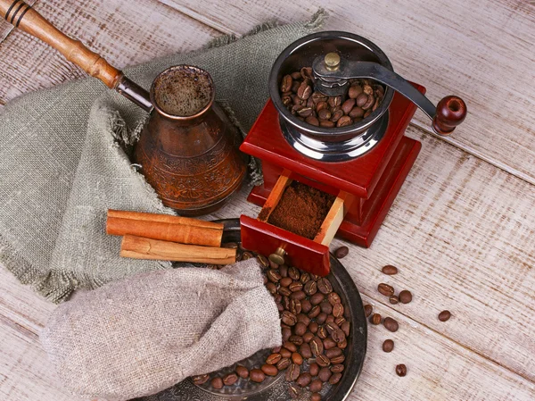 Coffee grinder, turk and cup of coffee on wooden background — Stock Photo, Image