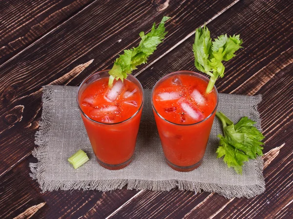 Bloody mary cocktails served with celery on wooden background — Stock Photo, Image