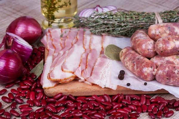 Red beans, thyme, sausages and bacon on wooden background — Stock Photo, Image