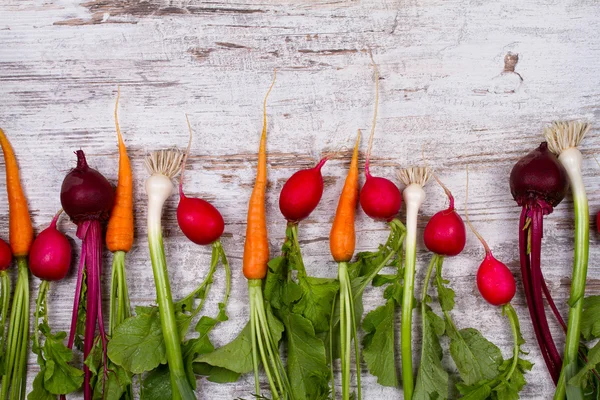 Zelenina na starý bílý stůl: baby mrkev, česnek, červená řepa, ředkvičky. Pohled shora, studio zastřelil — Stock fotografie