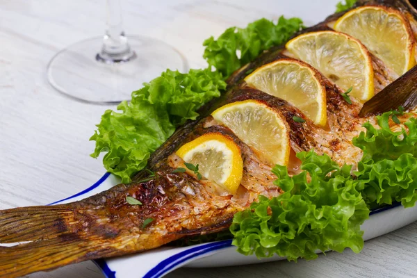 Karp cały grillowane ryby podawane z sałatką i cytryny; kieliszek wina — Zdjęcie stockowe