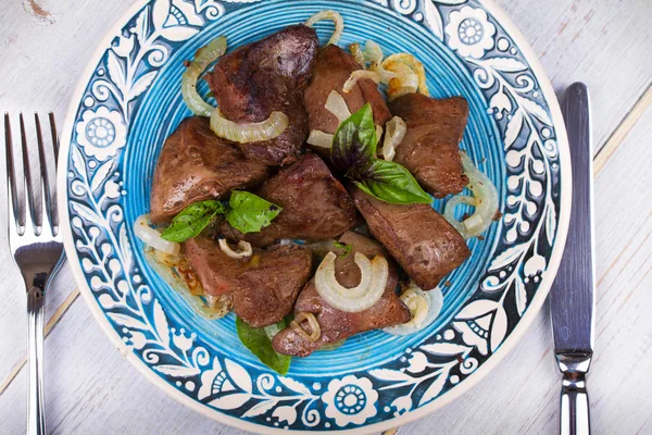 Sauteed liver with onions on blue plate. — Stock Photo, Image