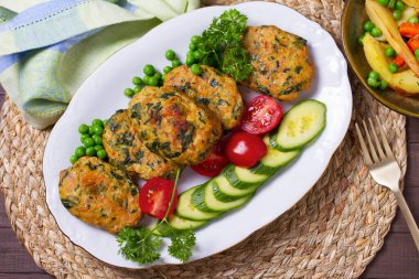 Kızarmış hindi ıspanaklı oval burger, yeşil bezelye ve salata. Yüksek açı görünümü