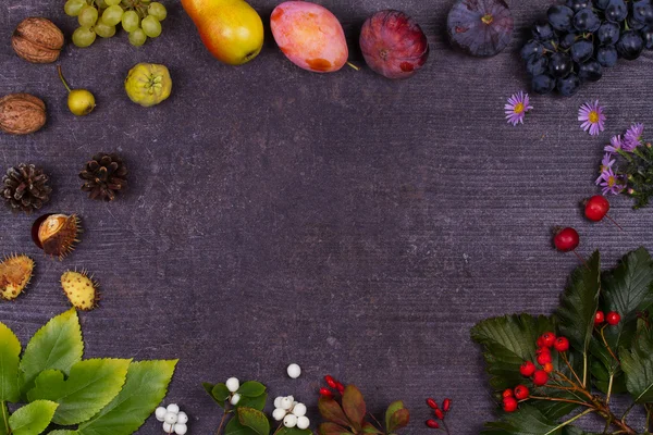 Stilleven met vruchten en aardbeien - appels, pruimen, druiven, peren, bladeren, dennenappels, vijgen, bloemen, kastanjes. Bovenaanzicht. Rustieke achtergrond met vrije tekst ruimte — Stockfoto