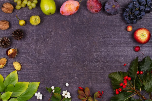 Naturaleza muerta con frutas y fresas: manzanas, ciruelas, uvas, peras, hojas, conos de pino, higos, flores, castañas. Vista superior. Fondo rústico con espacio libre de texto Imágenes de stock libres de derechos