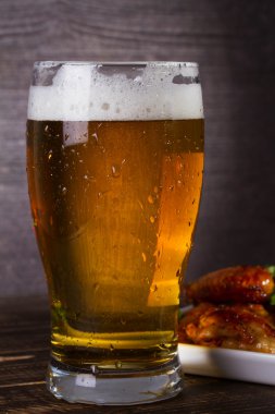 Bira ve tavuk kanatları koyu ahşap arka plan üzerinde bardak