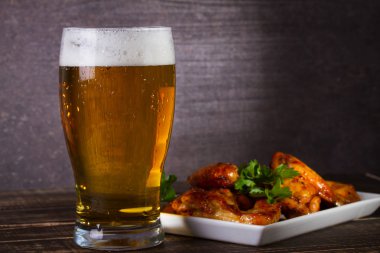 Bira ve tavuk kanatları koyu ahşap arka plan üzerinde bardak