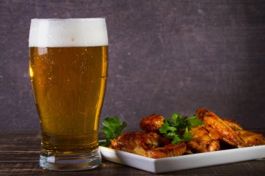 Bira ve tavuk kanatları koyu ahşap arka plan üzerinde bardak