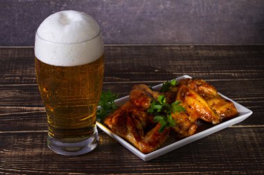 Bira ve tavuk kanatları koyu ahşap arka plan üzerinde bardak