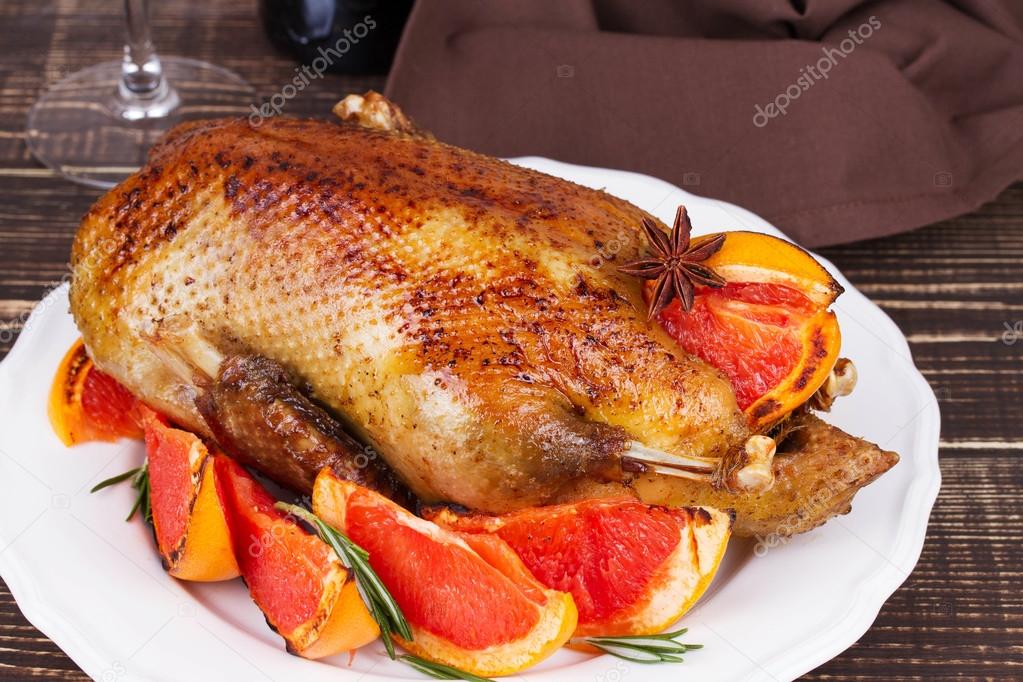 Festive Christmas duck baked with grapefruits and rosemary, glass of wine and candles