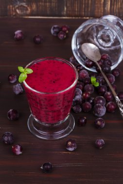 Koyu ahşap zemin üzerine nane ile süslenmiş güler yüzlü dondurulmuş yaz meyveleri