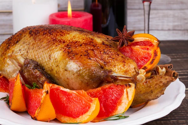 Slavnostní vánoční kachna pečený s grapefruity a rozmarýnem, sklo a láhev červeného vína. svíčky — Stock fotografie