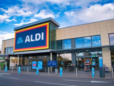 The frontage and brand logo of a branch of German discount retailer Aldi, taken in a local retail park on Wirral, UK on a sunny afternoon clipart