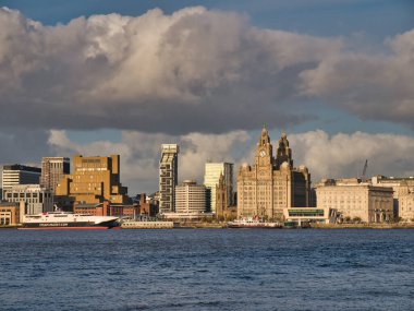 Liverpool 'un UNESCO limanına demirlemiş olan Man Adası ve Mersey Feribotları kıyıda listelenmiştir. Kraliyet Karaciğeri ve Cunard Binaları sağda görünüyor..