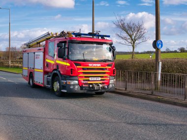 İngiltere 'de bir şehir yolunda kışın çekilmiş kırmızı bir İskandinav itfaiye aracı..