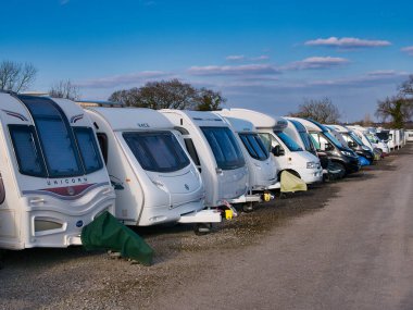 Kışın güneşli bir günde mavi gökyüzü olan güvenli bir karavan deposunda zorlu bir yolculukta olan bir grup beyaz karavan..