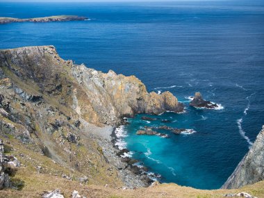 İngiltere 'nin Shetland kentindeki Unst adasındaki Clibberswick çevresindeki deniz kayalıkları ve turkuaz su - bu kayalar jeolojik olarak önemli olan Shetland Ophiolite Kompleksi - Metaharzburgite