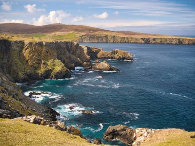 İngiltere 'nin Shetland kentindeki Unst adasındaki Clibberswick çevresindeki deniz kayalıkları ve turkuaz su - bu kayalar jeolojik olarak önemli olan Shetland Ophiolite Kompleksi - Metaharzburgite