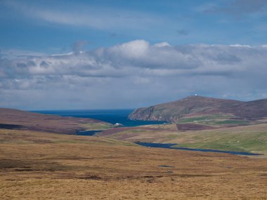 Valla Field 'dan Burra Firth' e kadar Shetland 'ın Unst adasında ve Saxa Vord' un tepesinde beyaz RAF radarlarıyla bir manzara. Güneşli bir baharda, açık bulutlarla çekildi..