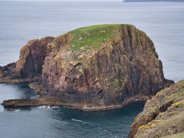 The Nev yakınlarındaki Westerwick, Mainland, Shetland, İngiltere 'de bulunan kırmızı granit Groni Stack - Sandsting Pluton - Granit. Devonian Dönemi 'nde yaklaşık 359 ila 393 milyon yıl önce Igneous Taşyatağı oluştu..
